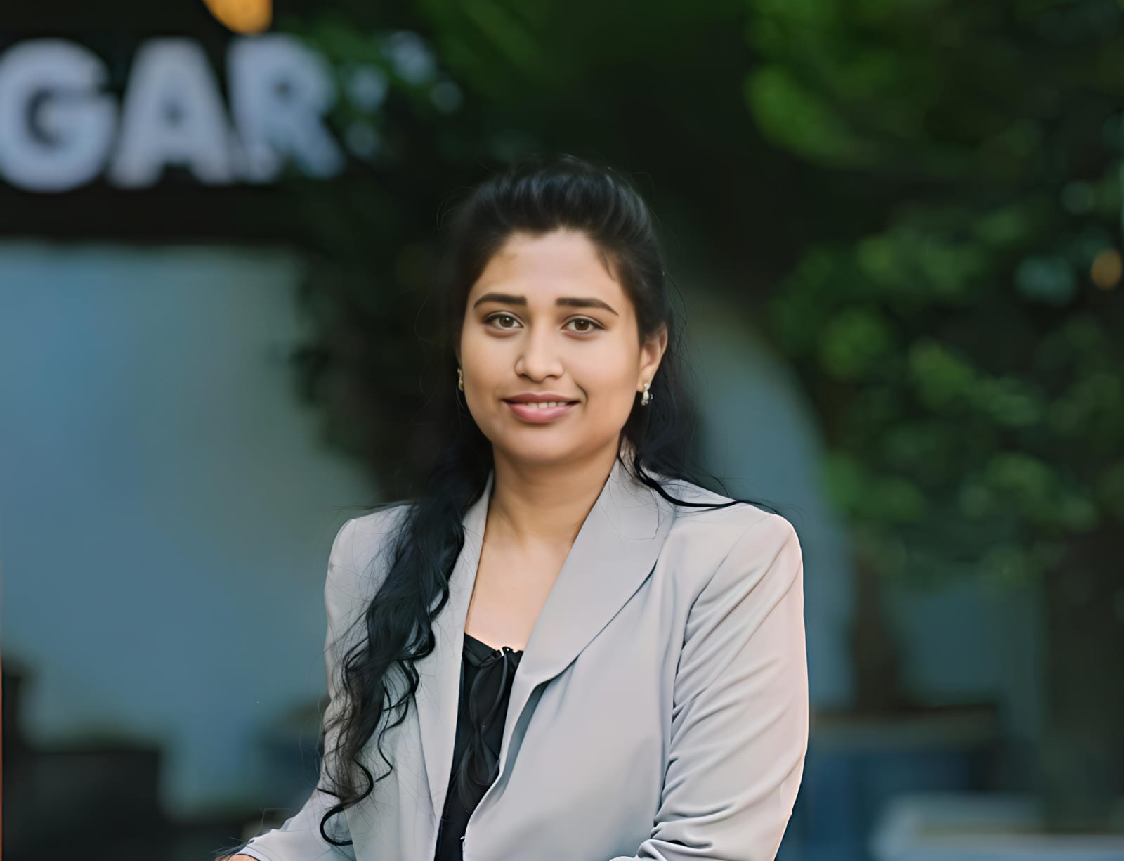 Portrait of a woman with black hair in front of a green background, smiling